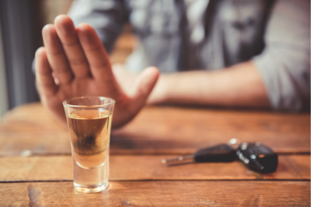 Man showing stop gesture and refusing to drink.