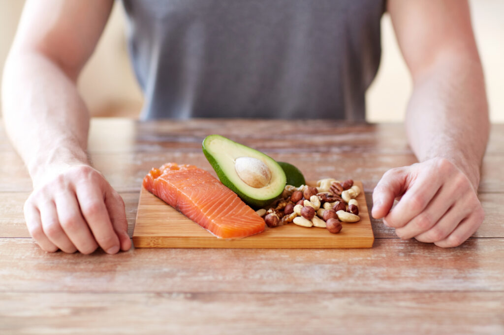 Close up of male hands with food rich in protein on cutting board.