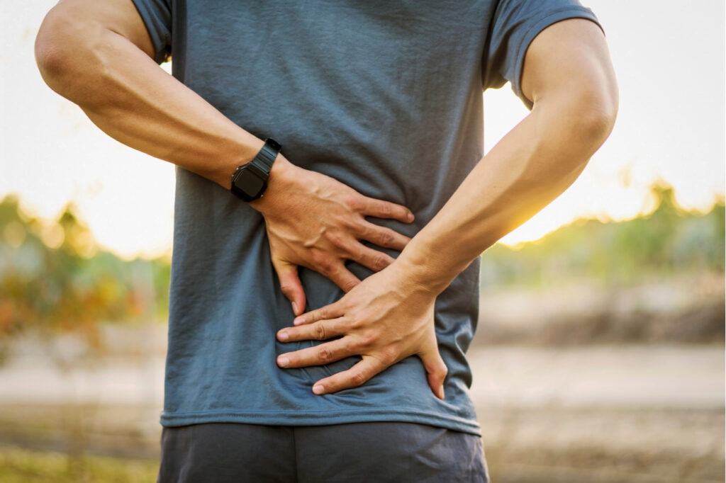 Back pain, close up young man has injury during outdoor exercise