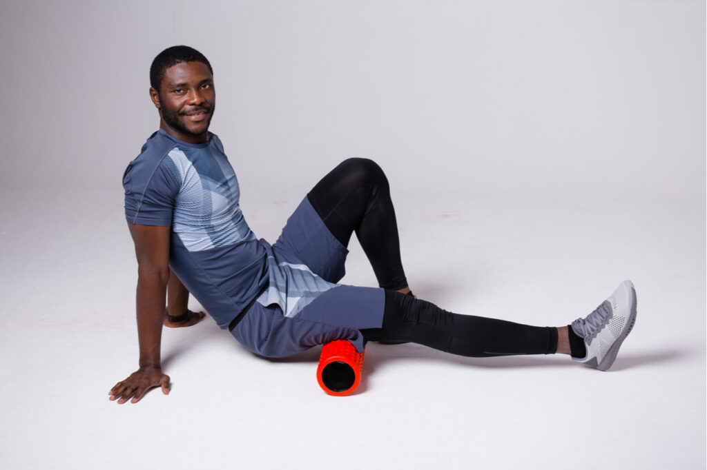 Pilates trainer exercising with massage cylinder.