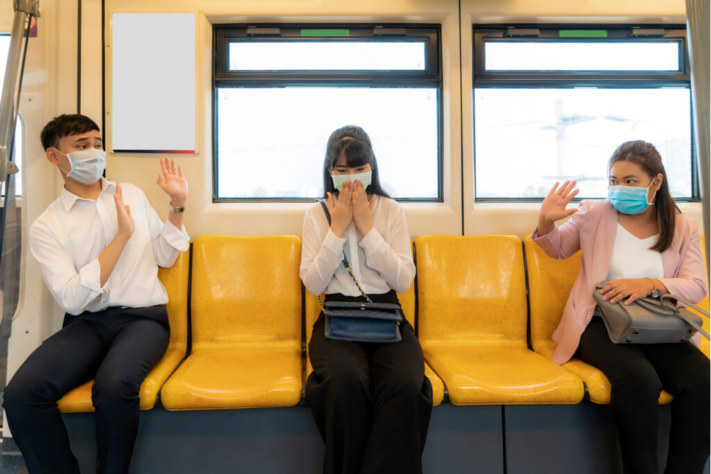 3 people sitting inside a passenger train while social distancing.