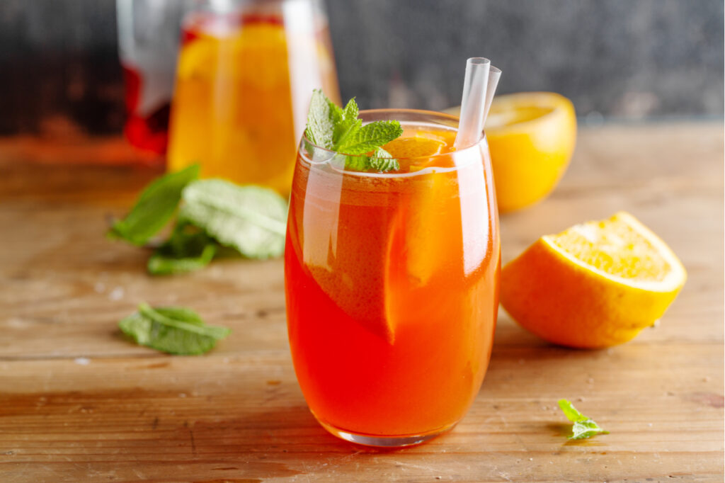 A glass of sunrise mocktail on wooden surface.