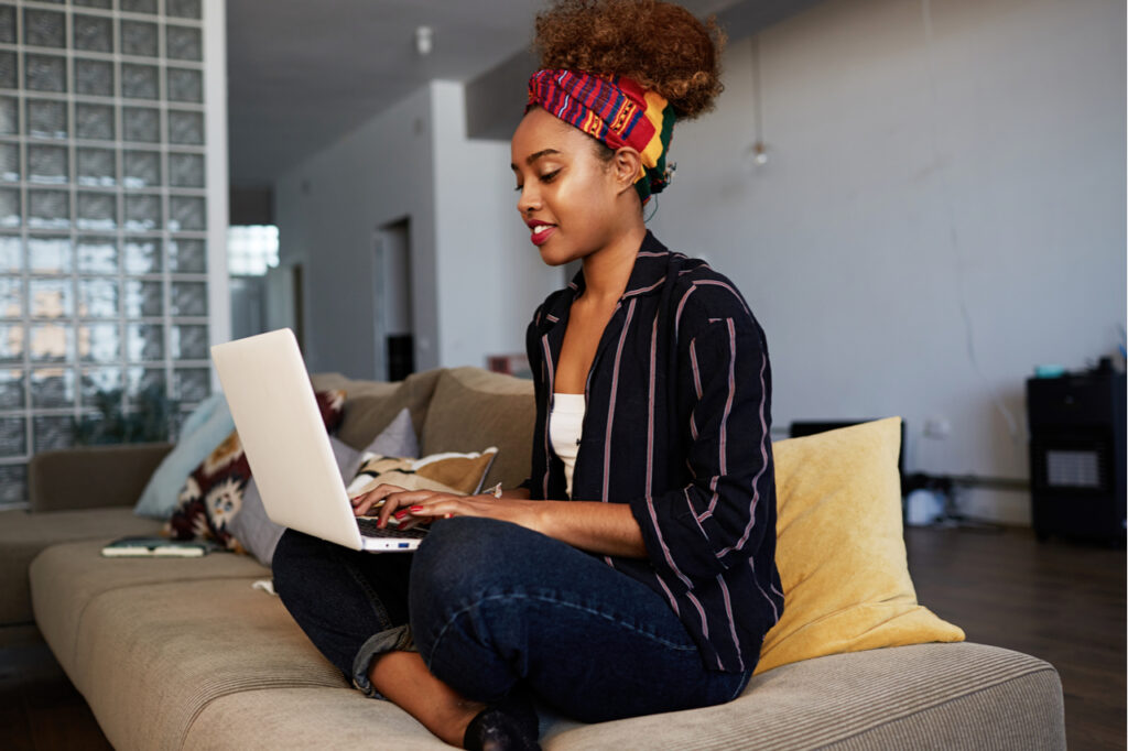Woman copywriter typing article for website on keyboard of laptop computer at home.