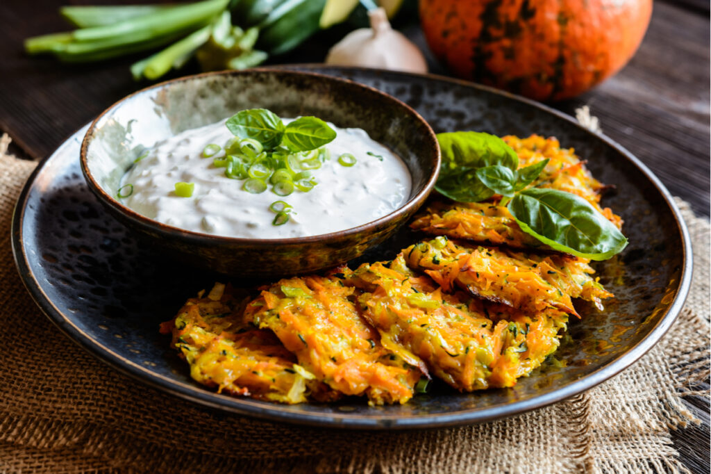 Zucchini fritters in a plate with a dip on the side.