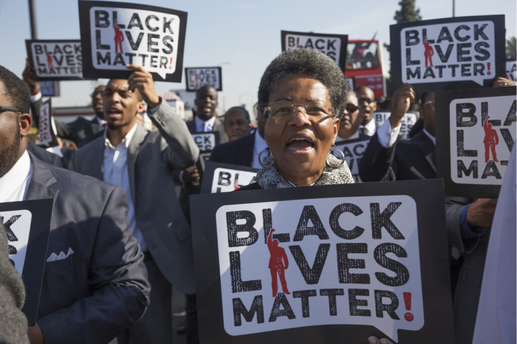 Woman holding a black lives matter sign in a crowd of protesters.