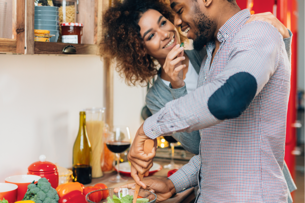 Young couple cooking playfully in the kitchen as valentine's day date ideas.