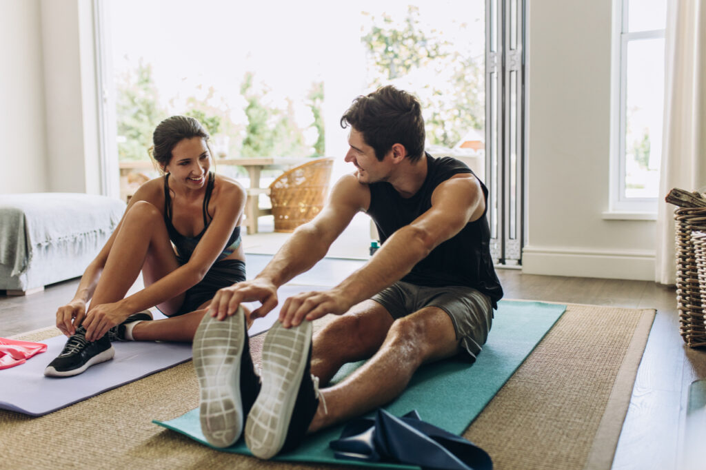 Couple exercising together. Man and woman in sports wear doing workout at home.