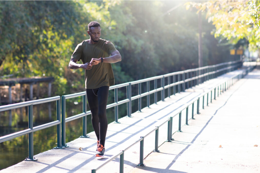 Black Man jogging and running beside road in park at autumn morning