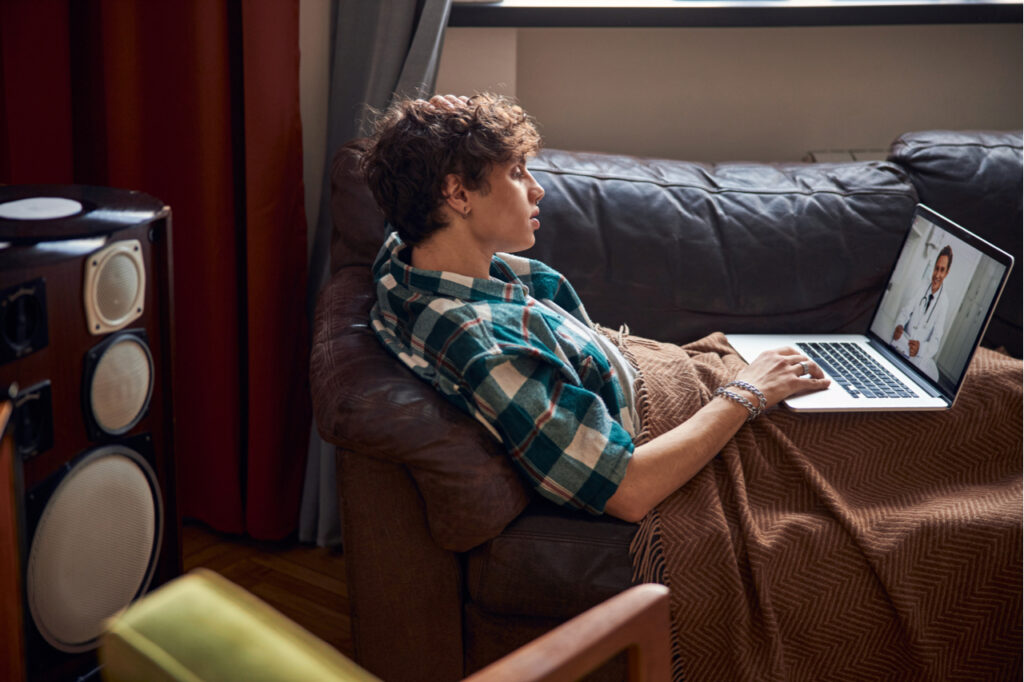 Attractive young man having online therapy with doctor at home.