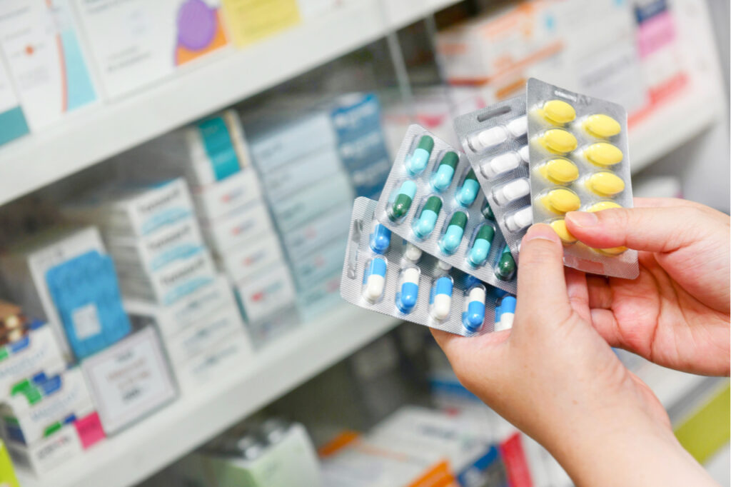 Hand holding medicine capsule pack at the pharmacy drugstore.