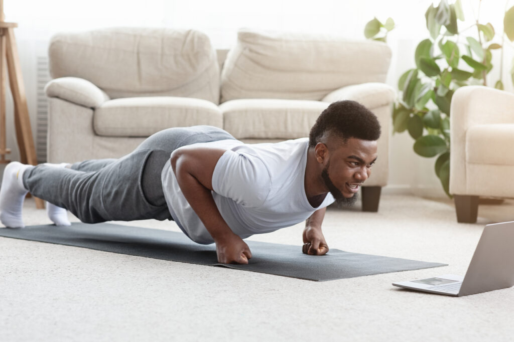 Man doing some planking while looking at his laptop.
