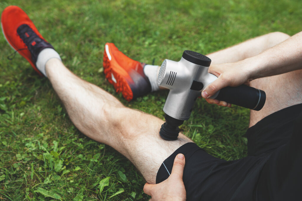 Man massaging leg with massage percussion device after workout.