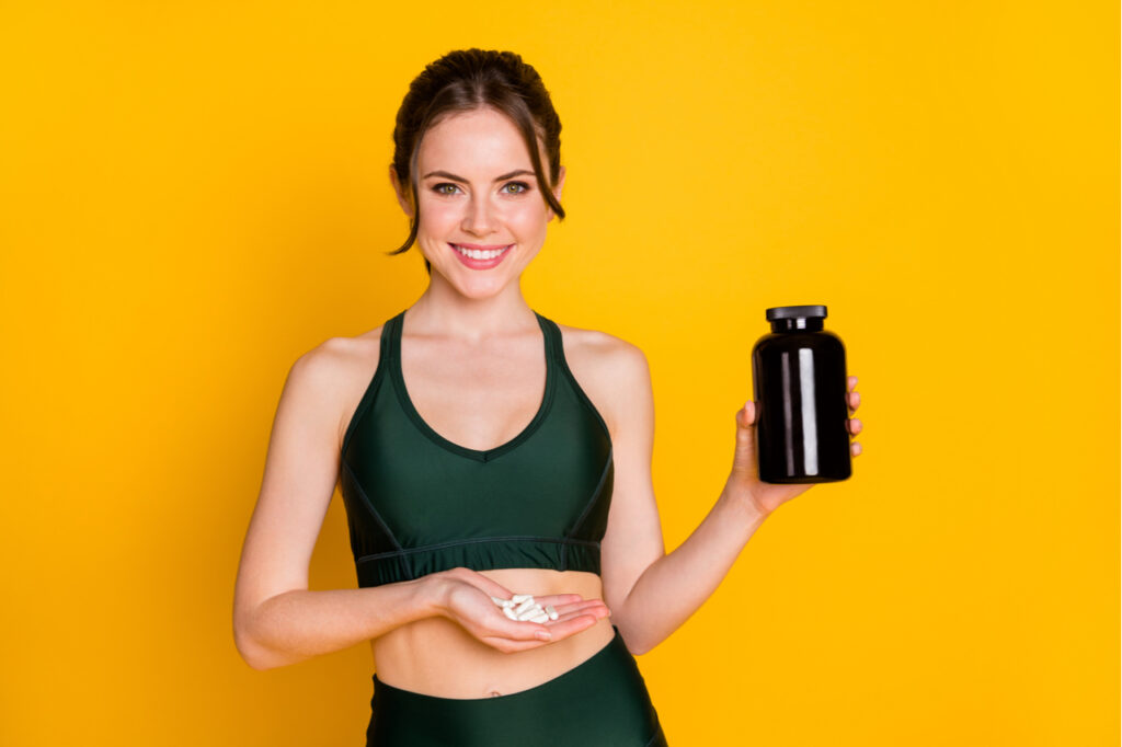 Woman taking supplement energy everyday regime isolated over bright yellow background