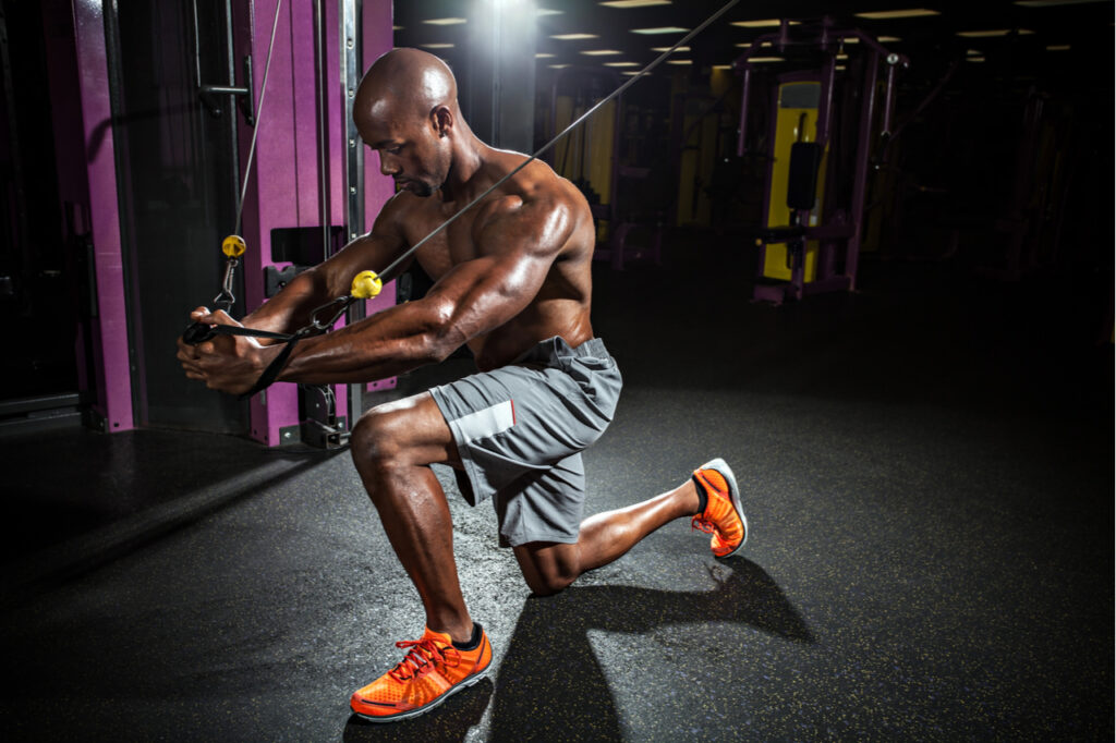 Muscular body builder working out at the gym doing chest fly exercises on the cable wire machine.