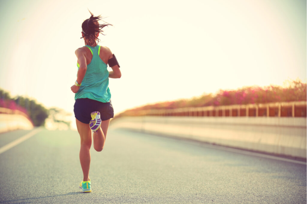 Young woman runner running on city bridge road wearing something like vionic women's brisk aimmy walking shoes.