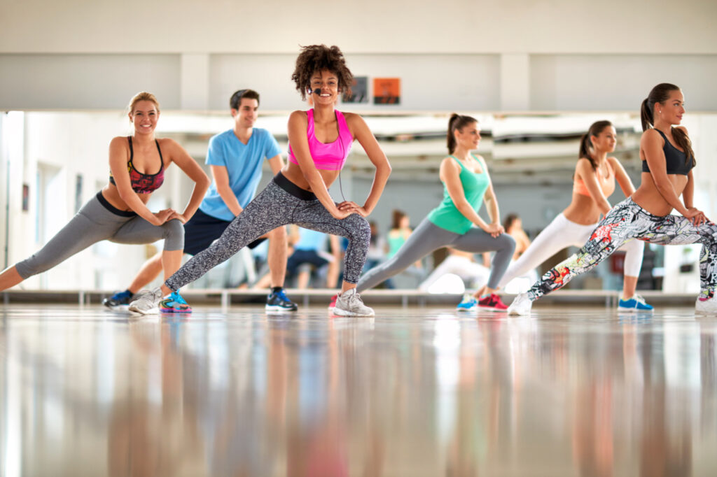 Young black curly trainer with group training aerobic at gym.