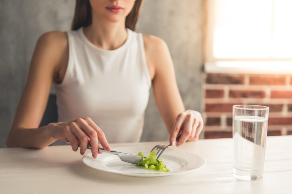 Eating disorder. Cropped image of girl eating lettuce