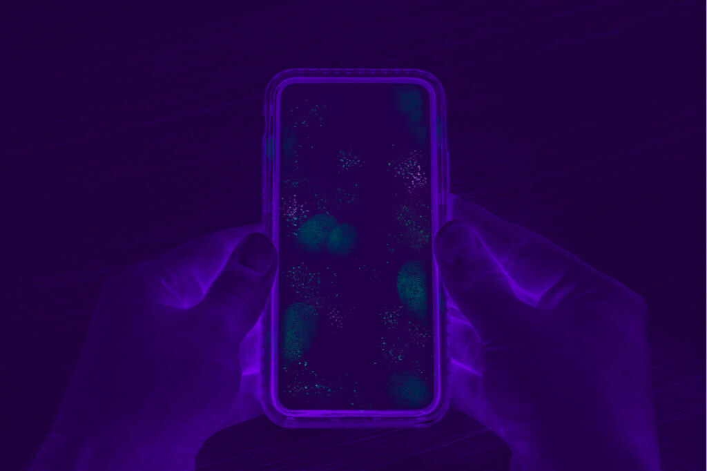 Hands holding cell phone with dirty contaminated touch screen that needs PhoneSoap 3.