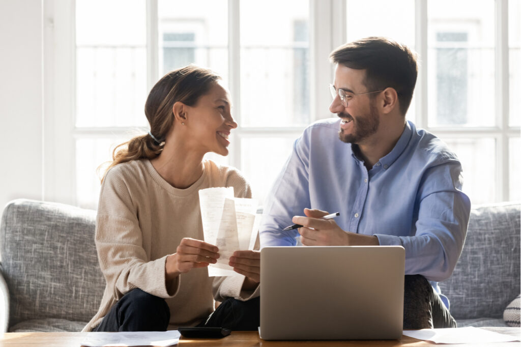 Couple sit on sofa busy with manage household budget.