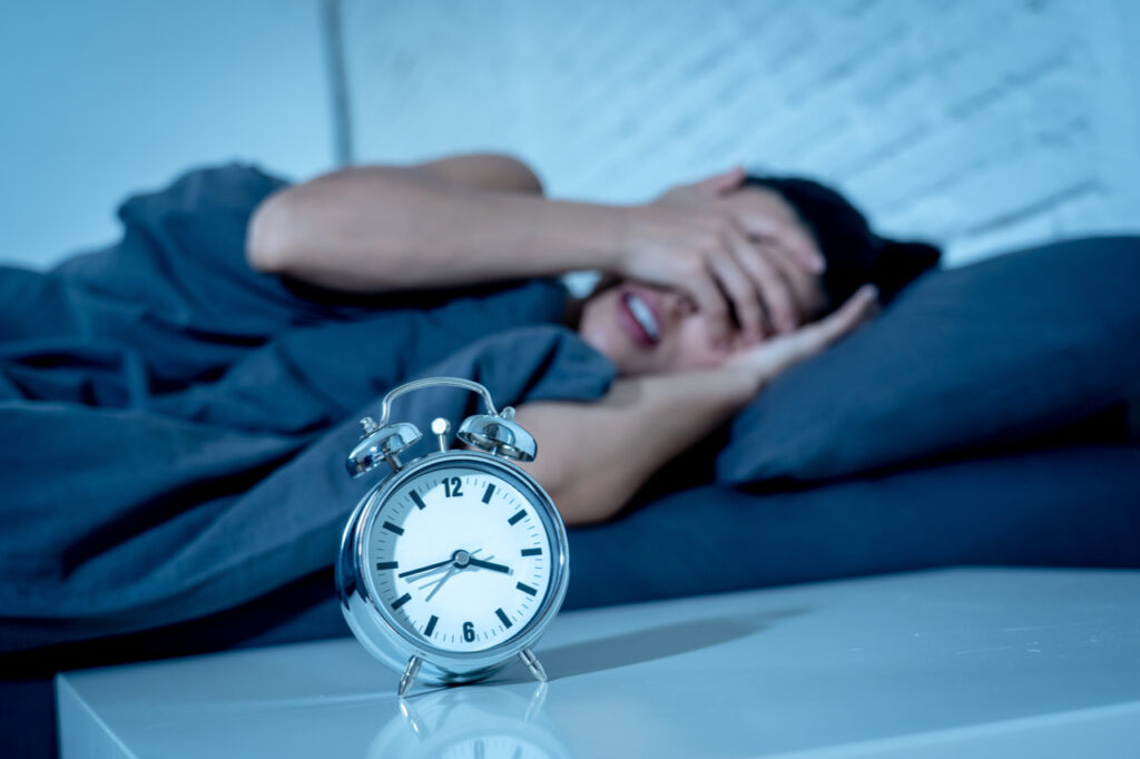 Woman at home bedroom lying in bed late at night trying to sleep suffering insomnia.