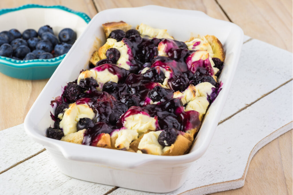 Close up of casserole dish with blueberry cream cheese French toast casserole and blueberry sauce.