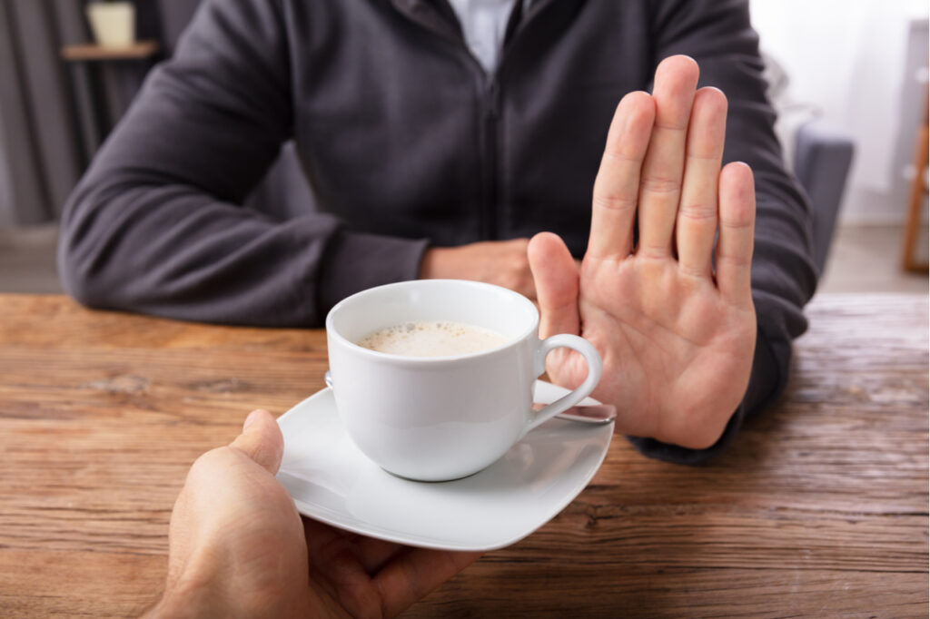 Man's hand refusing a cup of coffee.