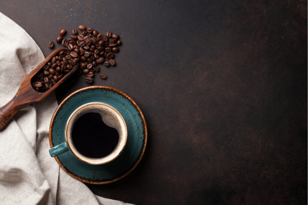 Coffee cup and beans on old kitchen table.