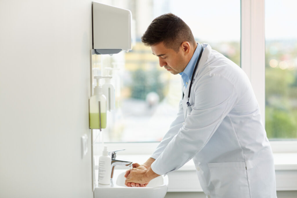 Doctor showing proper handwashing at medical clinic sink.