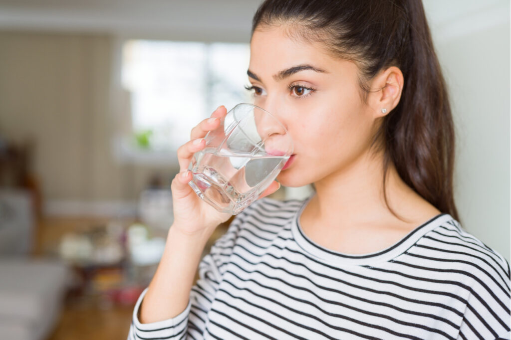 Young woman drinking a fresh glass of water at home.