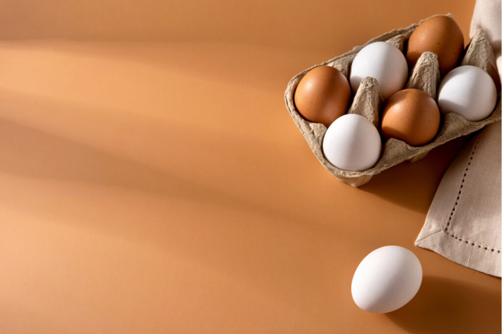 Brown and white chicken egges on beige background.
