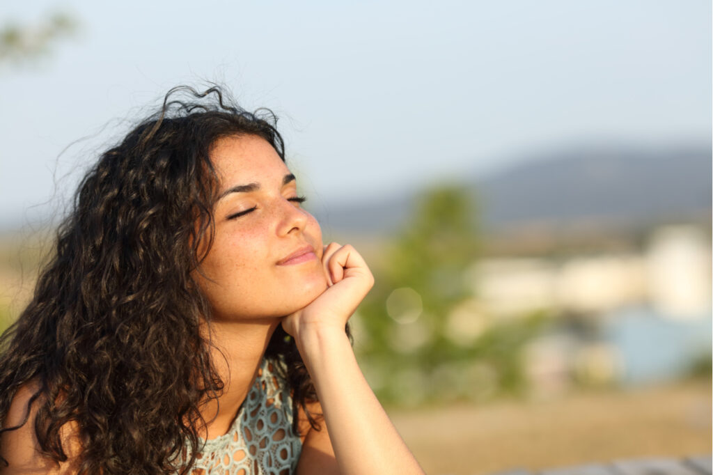 Woman relaxing and enjoying the sun in a warmth park at sunset.