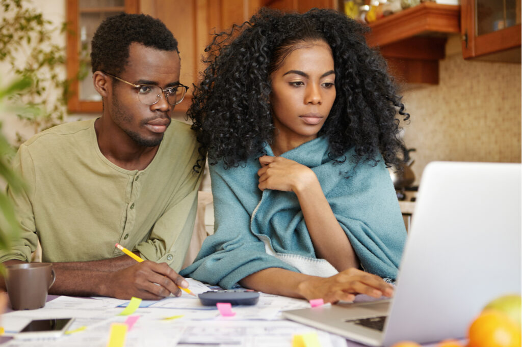 Couple doing paperwork together, sitting at kitchen table with piles of papers for financial independence.