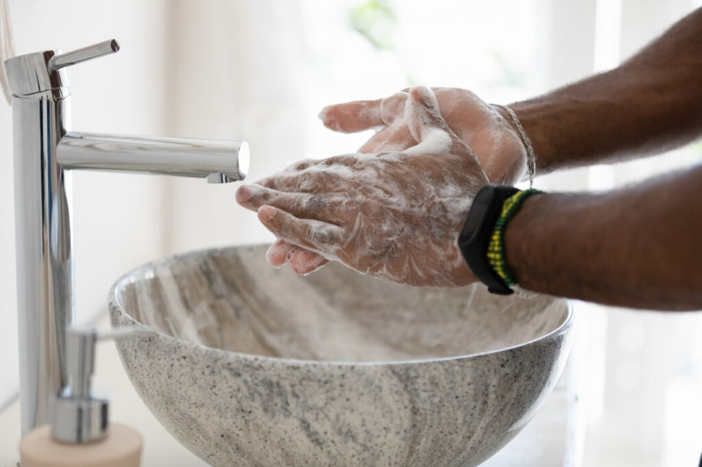 Man properly cleans hands with soap in bathroom.