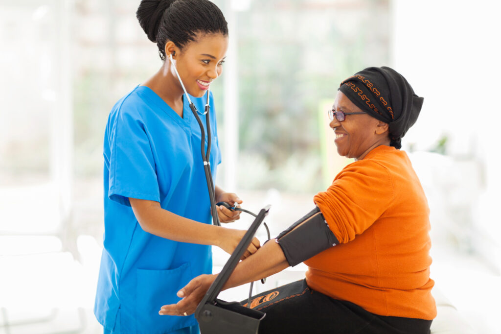 Smiling nurse checking senior patient's blood pressure.