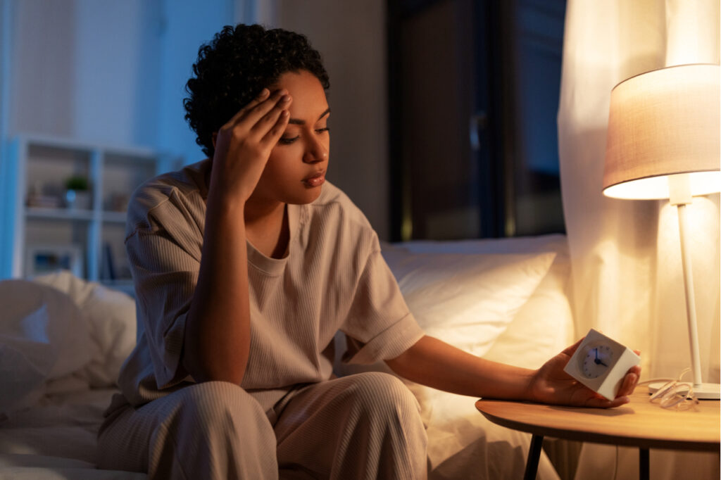 Woman looking at an alarm clock having a hard time sleeping.