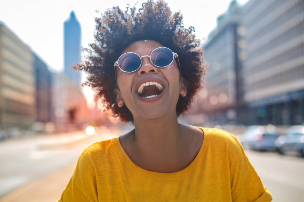 Cheerful girl laughs in the middle of a big avenue.