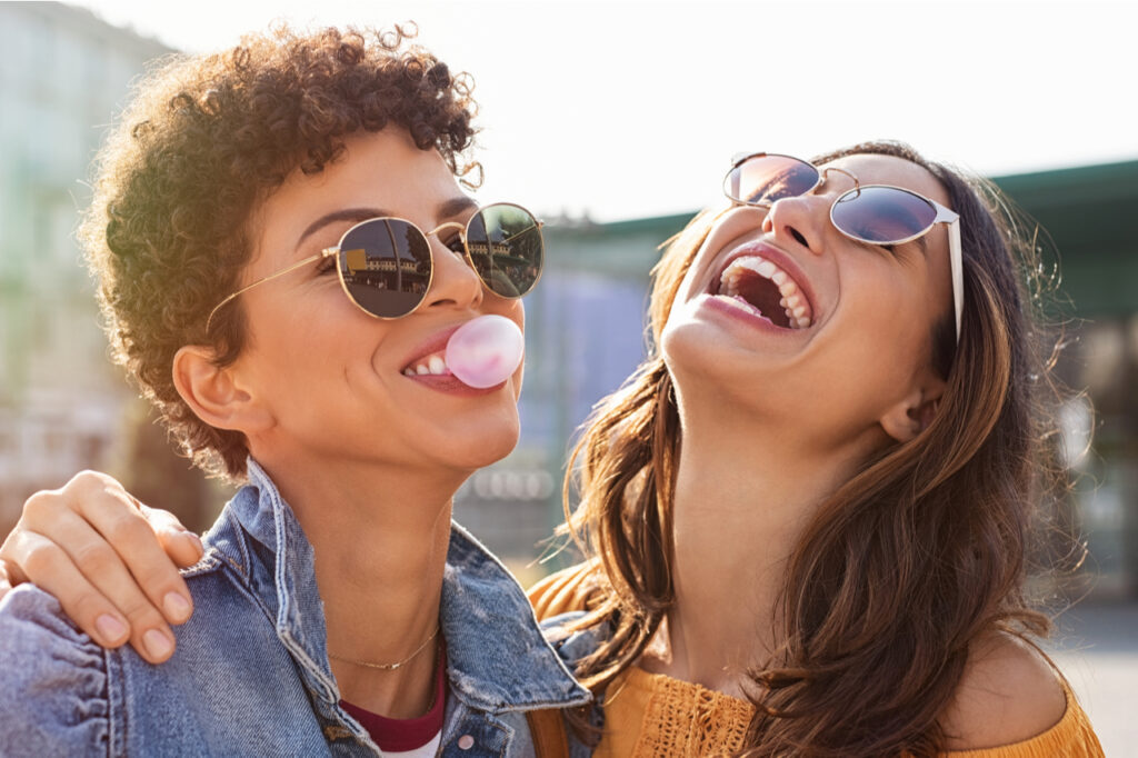 Woman laughing while friend inflating bubble gum.