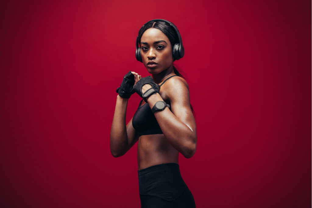 Woman wearing boxing gloves posing in combat stance looking at camera.
