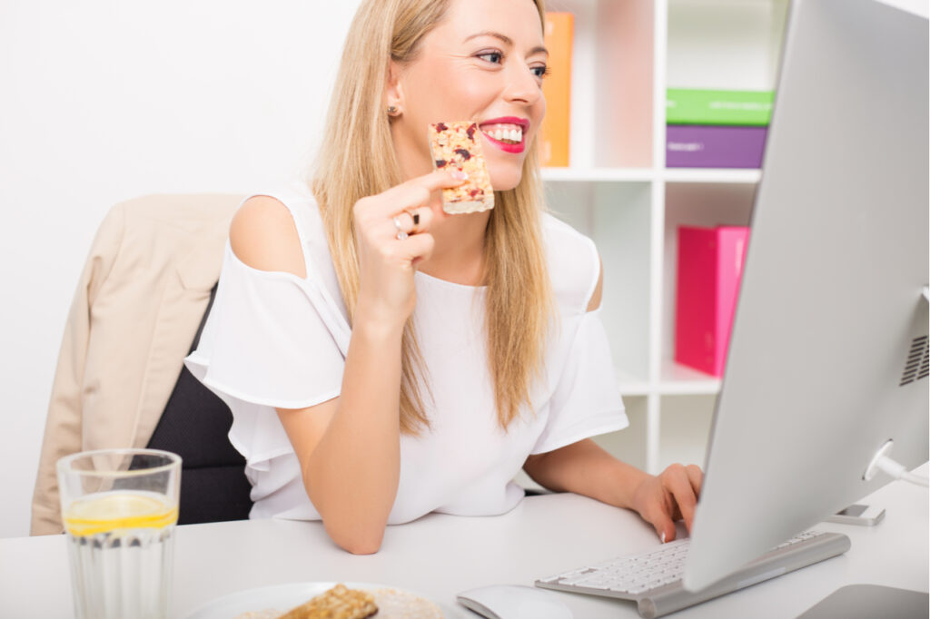 Woman having protein bar while working.