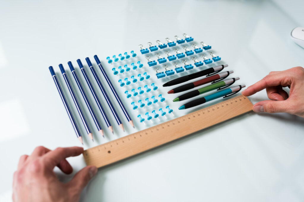 A person's hand arranging office supplies on the table.