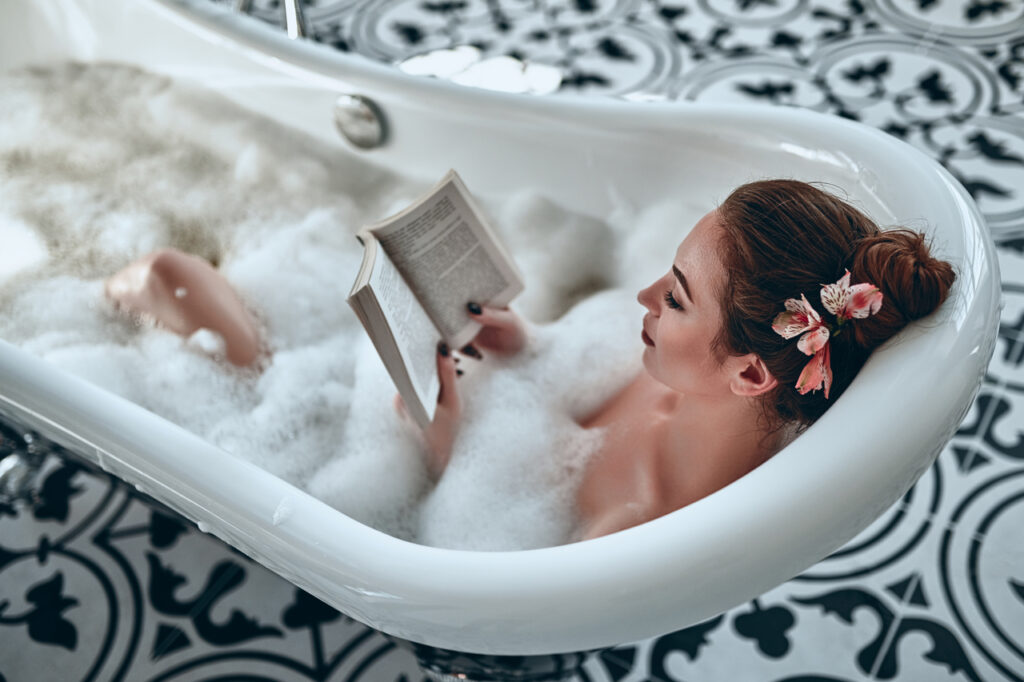 New mom having a bubble bath while reading a book.