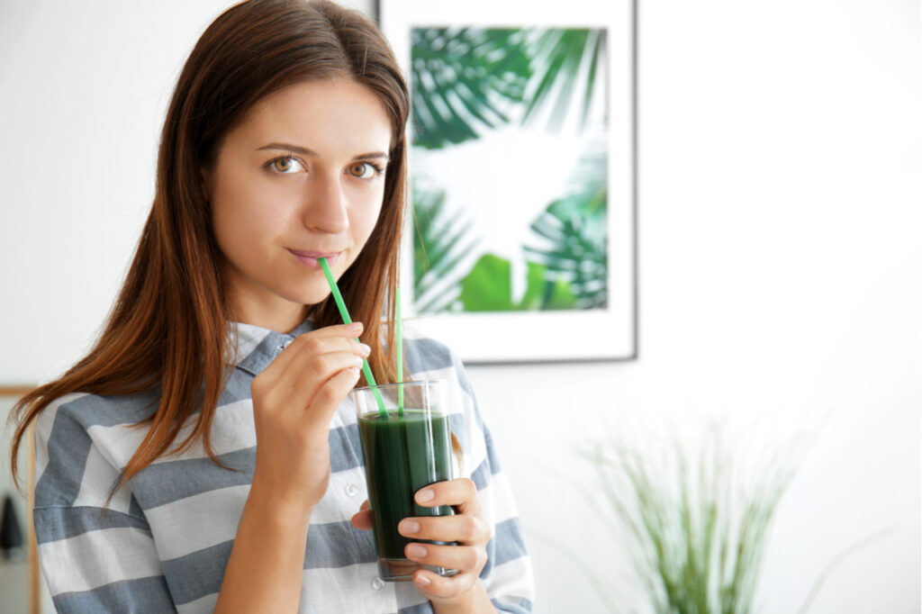 Woman drinking spirulina cocktail on indoors.