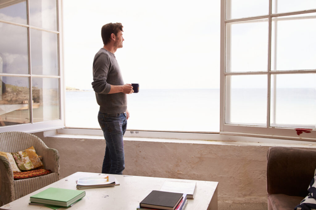 Man Standing At Window And Looking outside.