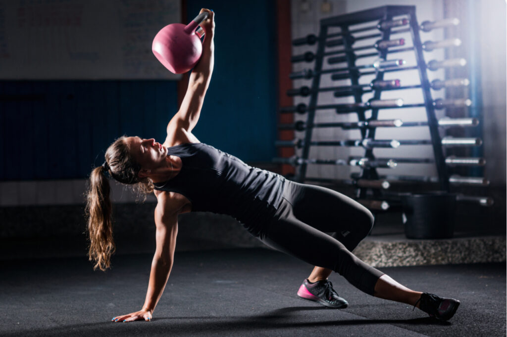 Woman athlete exercising with kettlebell indoors.