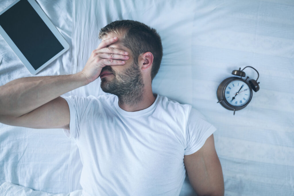Tired man experiencing sleep effect on mental health.