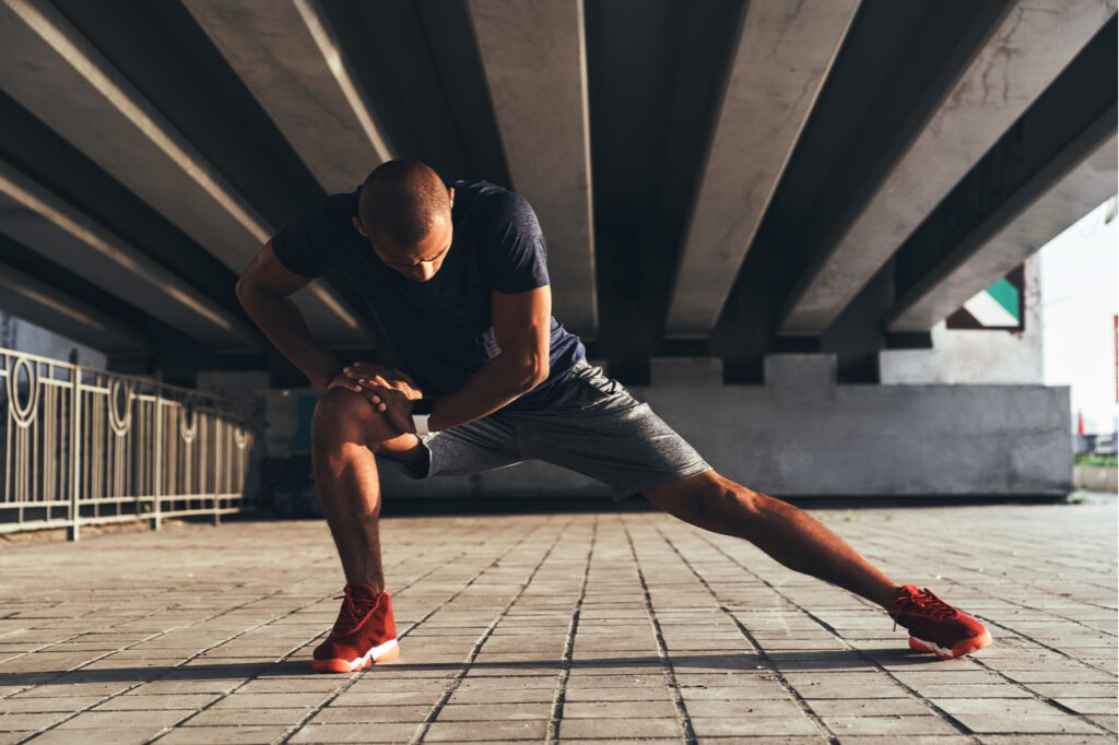 Man in sports clothing stretching while warming up outdoors.