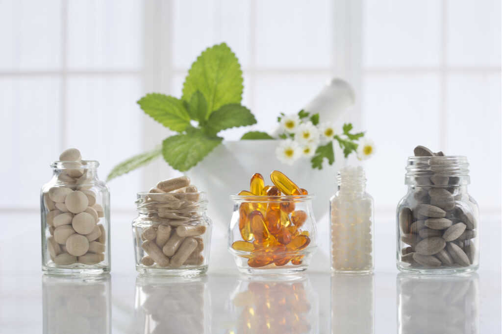 Herbal medicine pills and mortar over bright background.