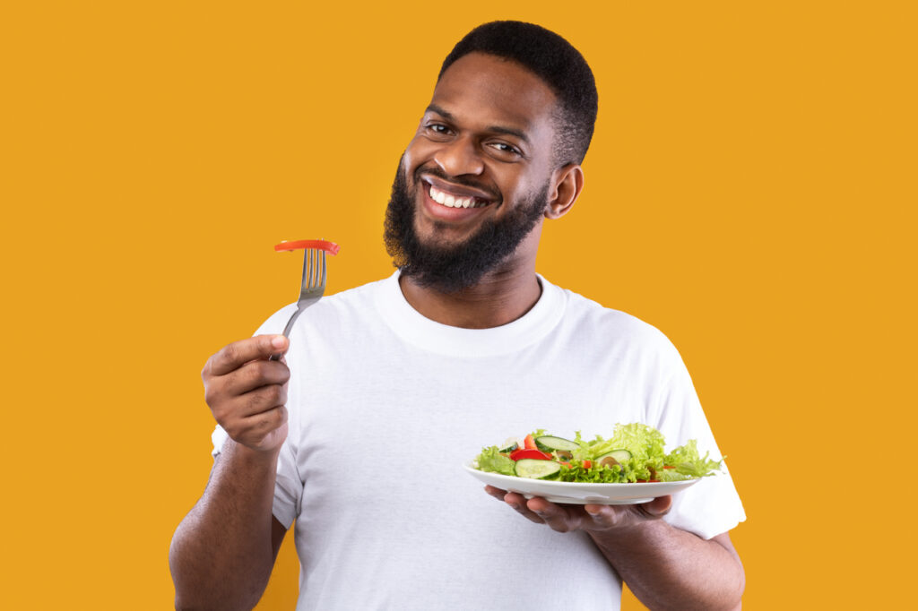 Cheerful guy eating salad getting his vegan protein.