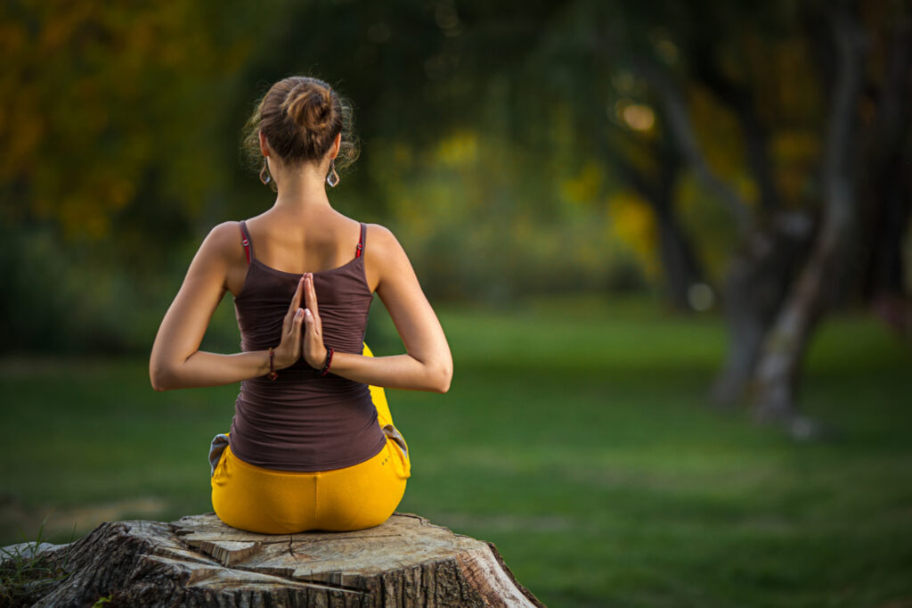 Young woman doing yoga exercises in the autumn city park.