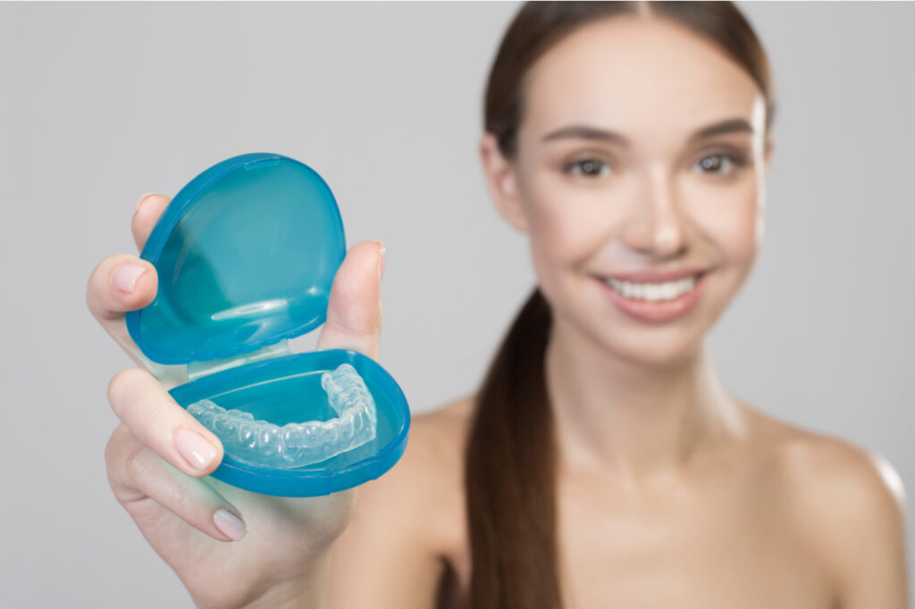 Close up of plastic transparent brace in hand of positive young woman.